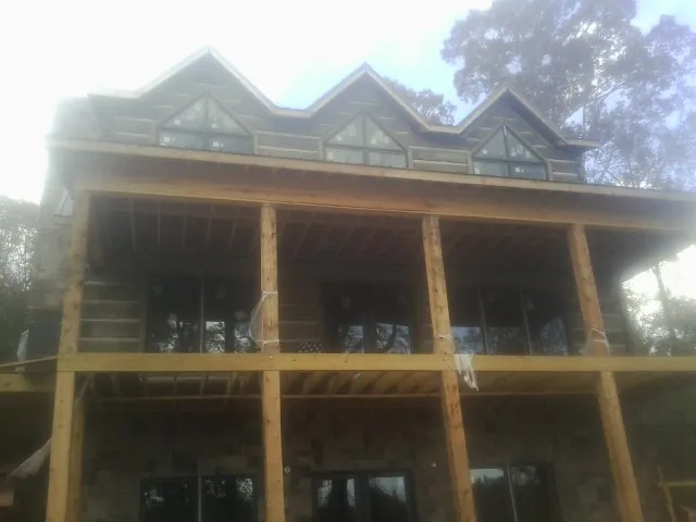 Dormers and porch framing on a large log home under construction — Roof Coating work by our crew in Gregory