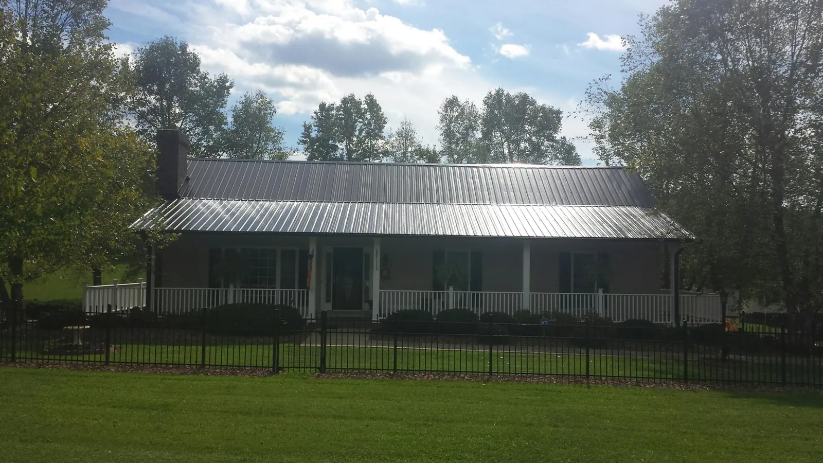 Gray metal roof on a brick ranch with a full width front porch — Gutter Guard Installation work by our crew in Gregory