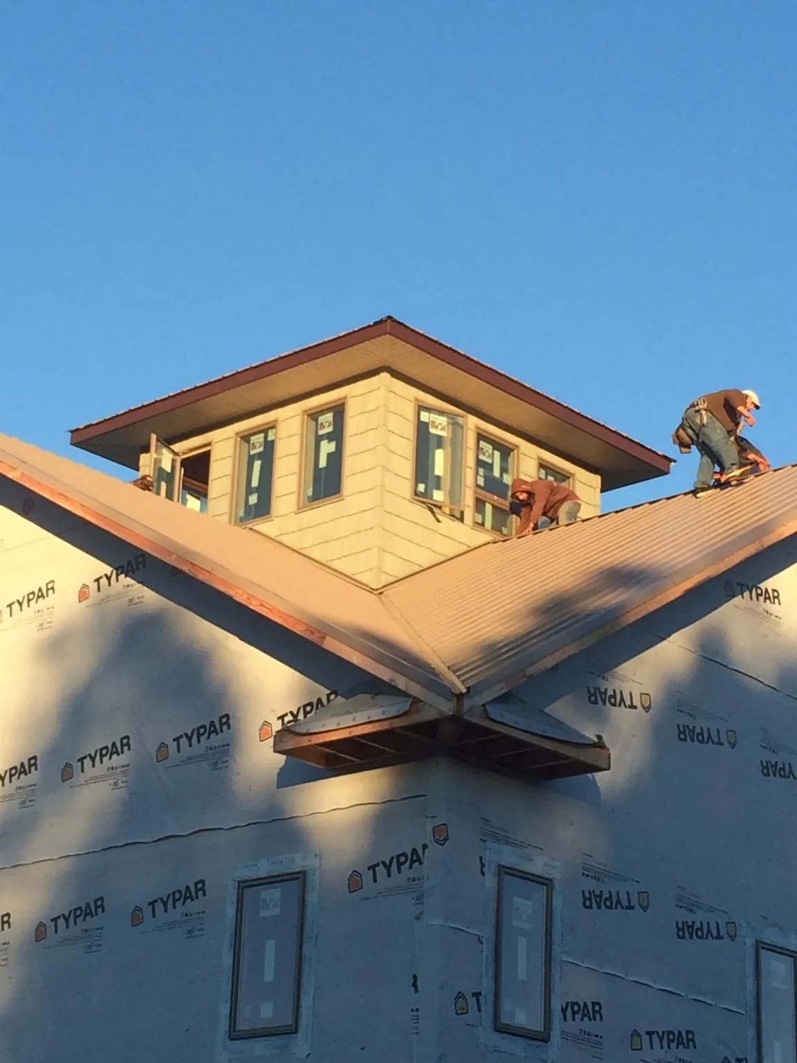 Roofers working around a rooftop cupola on a new metal roof at sunset — Roof Waterproofing in Gregory by Roofing Brothers